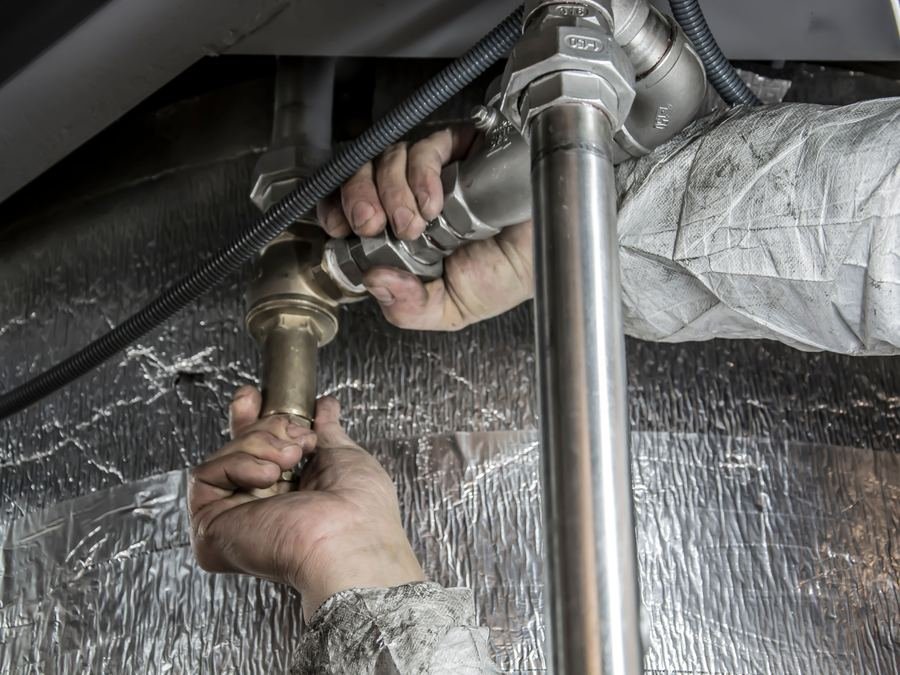 Fontanero instalando tuberías bajo un fregadero
